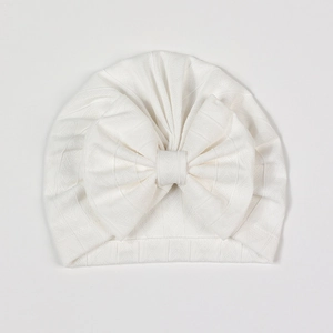 Close-up of white newborn baby hat with hollow geometric diamond knit texture and bow