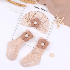 Detailed view of beige knit baby bonnet and socks set with 3D floral accents
