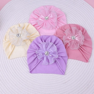 Détail de turbans pour bébé avec fleur en résille et strass sur tapis tissé