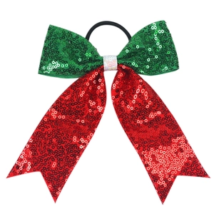 Detail of red, green, and white sequin bow hair tie with long ribbons and black elastic