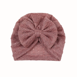 Détail du turban bébé avec grand nœud et motif tricoté en forme de cœur évidé