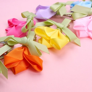Barrettes tulipes en ruban coloré avec nœuds verts sur fond rose vue détaillée