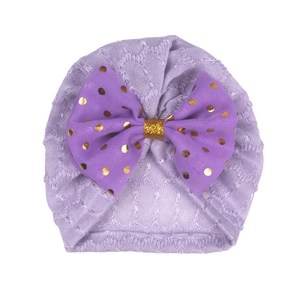 Détail du turban violet pour bébé avec un nœud décoratif doré à pois brillants