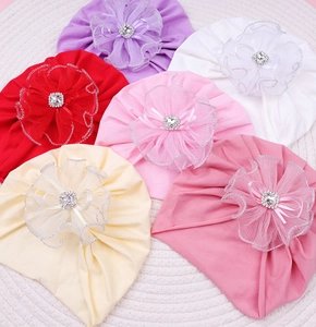 Détail de turbans bébé avec grandes fleurs en résille et strass carrés en couleurs assorties