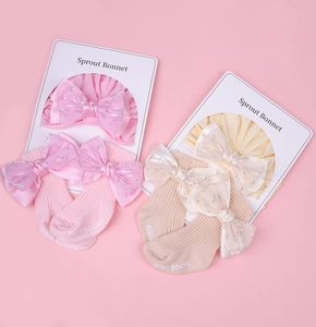 Détail d'un ensemble bonnet et chaussettes pour bébé en coton avec nœuds en tulle brillant