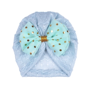 Détail d'un bonnet tricoté bleu clair pour bébé avec un nœud en mousseline menthe