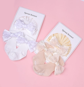 Détail du coffret cadeau bébé avec bandeaux à nœuds pailletés et chaussettes roses