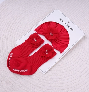 Détail du bonnet rouge tricoté et des chaussettes à fleurs pour bébé sur carte