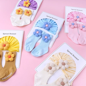 Close-up of soft cotton baby bonnet and matching floral socks in various pastel colors
