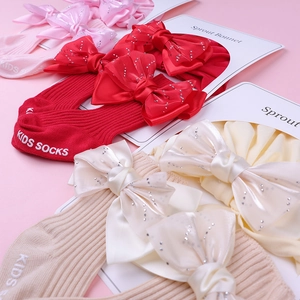 Détail de chaussettes bébé en coton côtelé avec grands nœuds en satin et strass