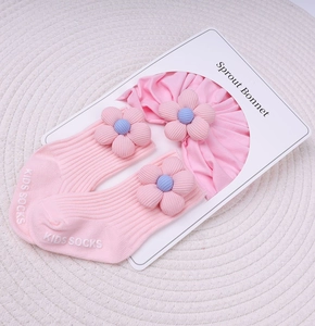 Détail d'un ensemble bonnet et chaussettes roses pour bébé avec fleurs 3D en tissu