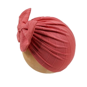 Pink newborn turban hat with geometric texture and a large decorative bow for girls