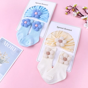 Detailed set of knit baby bonnet and matching floral socks on a gift display card