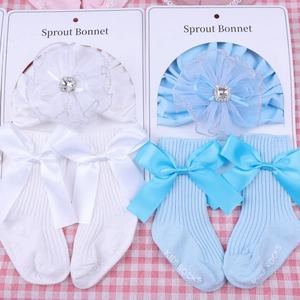 Close-up of lace flower baby bonnet and knit socks with satin bows in white and blue