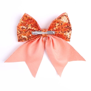 Detail view of sparkly sequin bow hair clip with satin ribbons and metal duckbill clip