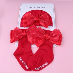Détail de l'ensemble bonnet et chaussettes en coton rouge pour bébé avec nœuds strass
