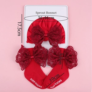 Detailed view of red knitted baby bonnet and socks set with elegant lace bow accents