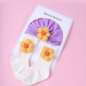 Close-up of purple baby beanie and white ribbed socks with 3D yellow fabric flowers