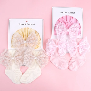 Detailed view of baby bonnet and lace bow socks set in cream and pink colors