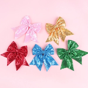 Detailed view of five colorful sequin embroidered bow hair clips for girls in a flat lay setup