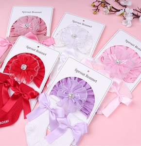 Detail of newborn baby hat and socks set with lace flowers and bowknot ribbons