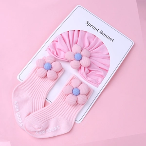 Detail of pink cotton baby turban and socks set with 3D floral accents and ribbed texture