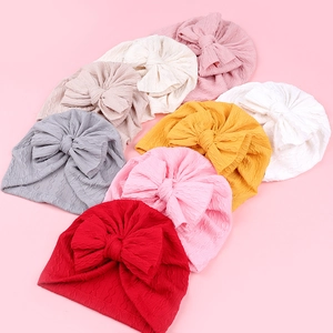 Turbans pour bébés en tricot côtelé avec grand nœud en diverses couleurs douces sur fond rose