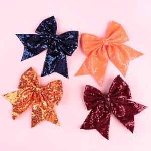Detailed view of four sequined bow hair clips in navy blue, orange, gold, and burgundy