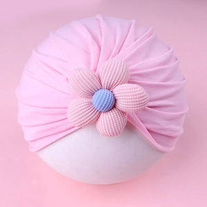 Detailed view of pink knitted baby turban hat with a 3D floral decoration and pleated design