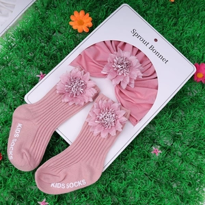 Ensemble bonnet turban rose et chaussettes à fleurs pour nouveau-né sur l'herbe