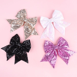Close-up of sparkling sequin bow hair clips in champagne, white, black, and rose red colors