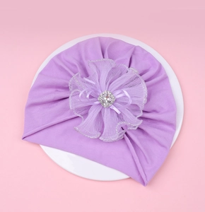 Détail du turban violet pour bébé avec une fleur en résille et un cristal carré au centre