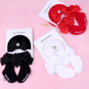Détail de l'ensemble bandeau bébé avec nœud et chaussettes en rouge, noir et blanc