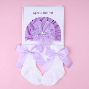 Flat lay of newborn baby headband and cotton socks with purple floral rhinestones