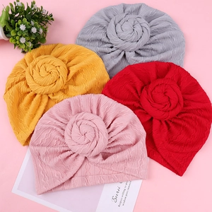 Flat lay of colorful baby turbans in pink, red, yellow, and grey with a top knot detail