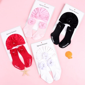 Vue à plat d'un ensemble bonnet et chaussettes pour bébé avec fleurs 3D en plusieurs couleurs