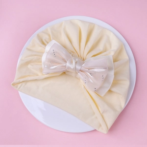 Détail du bonnet bébé en coton avec nœud en maille rose et strass scintillants