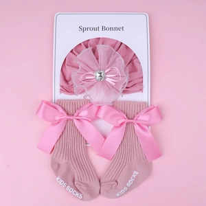 Pink newborn baby bonnet with lace flower and matching ribbon bow socks set on card