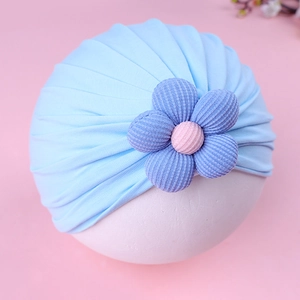 Close-up of soft light blue baby turban hat with a purple corduroy flower detail