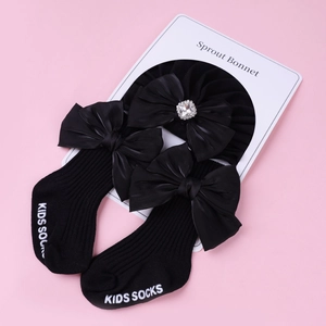 Vue détaillée du béguin bébé avec strass et chaussettes noires à grand nœud en satin