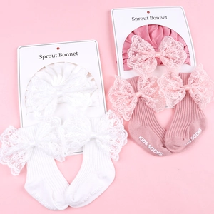 Detail of baby lace bow headband and striped cotton socks set on soft pink background