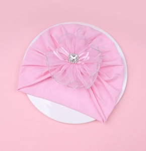 Détail d'un turban pour bébé rose avec grande fleur en tulle et strass carré brillant