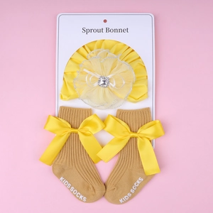 Detailed view of yellow infant lace flower headband and ribbed socks with satin bows