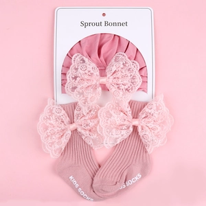 Close-up of pink knit baby bonnet and socks set with elegant lace bow details