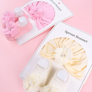 Vue détaillée du bandeau bébé avec fleurs et chaussettes assorties sur fond rose