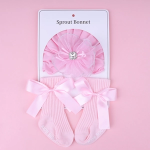 Detailed view of pink newborn gift set featuring lace floral headband and satin bow socks