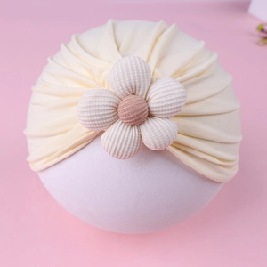 Detail of baby turban hat with a large 3D fabric flower and soft pleated knit texture