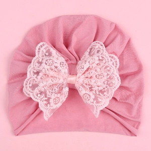 Detailed close-up of a pink infant turban hat with a large floral lace bow accent