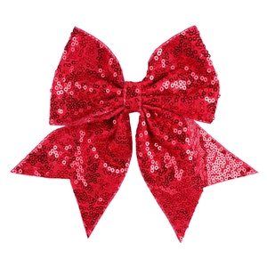 Close-up detail of a large red sequined bow hair clip with shimmering metallic texture
