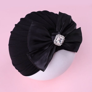 Détail d'un turban noir pour bébé avec un grand nœud plissé et un strass étincelant